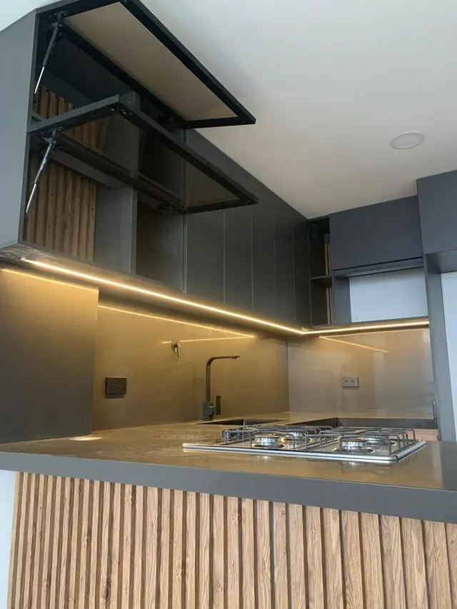 Cocina oscura con iluminación LED y puertas abatibles