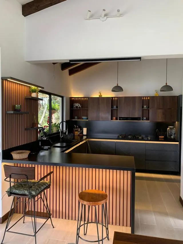 Cocina en U con barra en listones de madera y luces LED