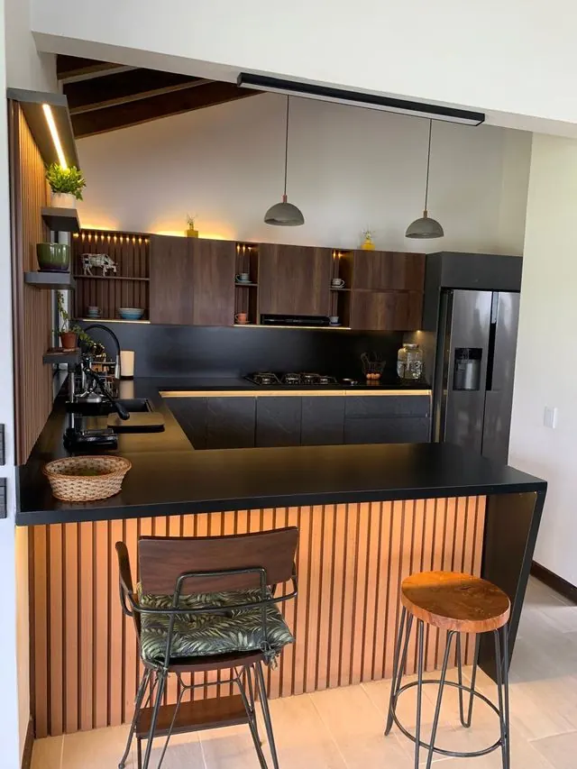 Cocina con barra desayunador, nevera y alacenas en madera oscura