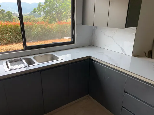 Mesón en porcelanato tipo mármol con lavaplatos y muebles bajos grises