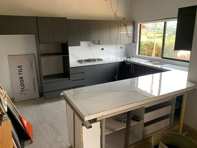 Cocina en U con mesón y salpicadero en porcelanato tipo mármol, en instalación