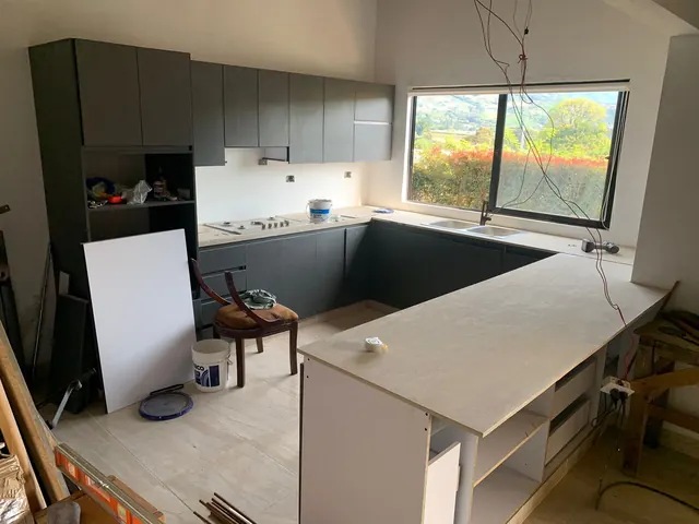 Cocina en U en instalación con módulos gris oscuro y mesón en proceso