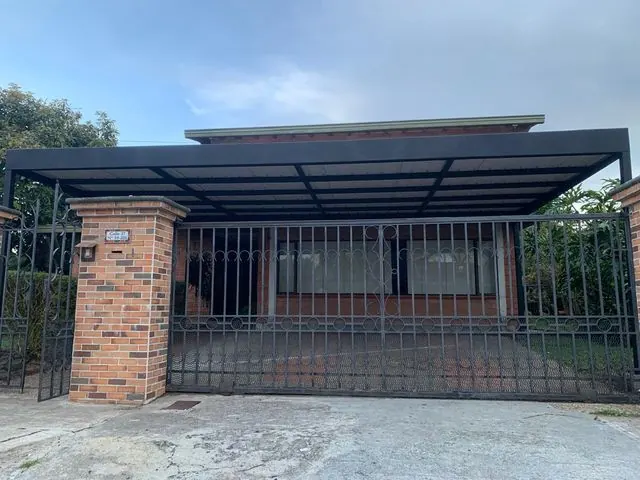 Pérgola metálica sobre parqueadero y portón de vivienda