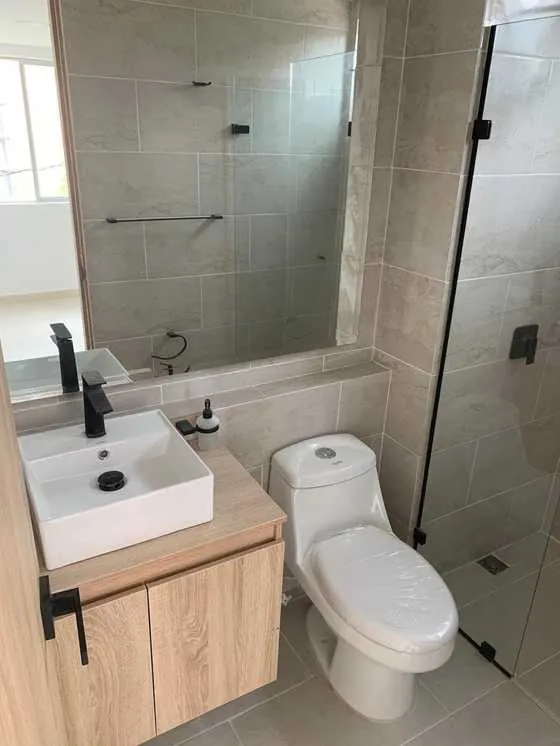 Baño moderno remodelado con grifería negra y enchape mármol